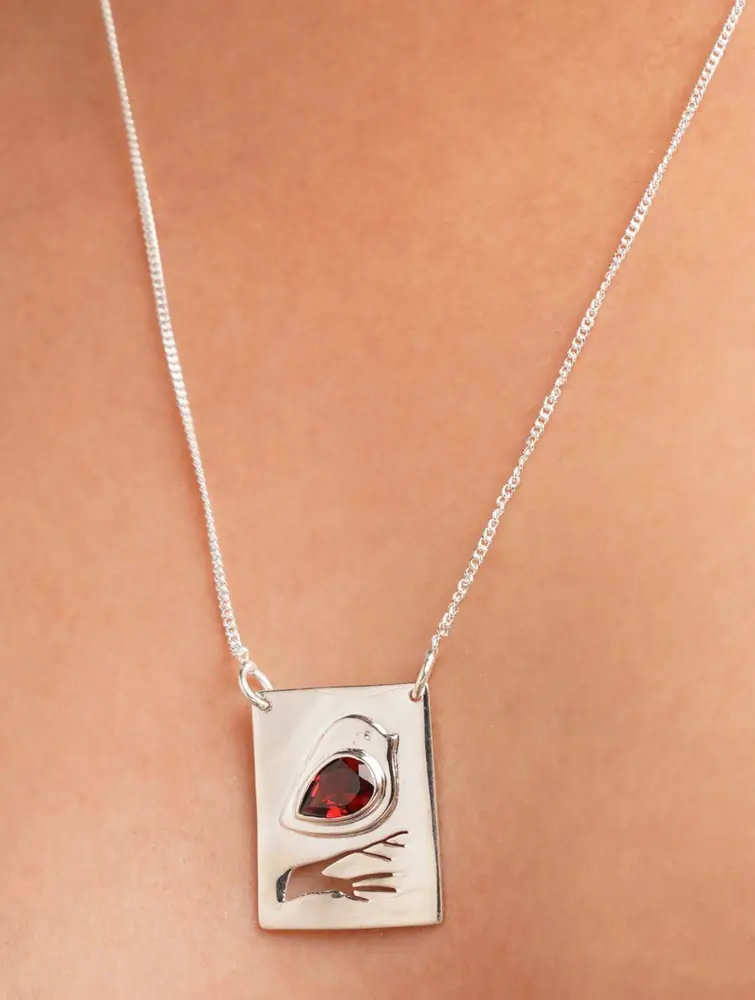Close view of the square pendant with a dark red stone