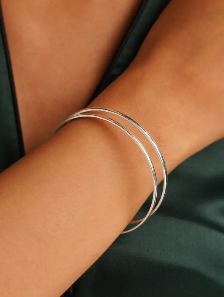 Model wearing two slim bangles on one wrist