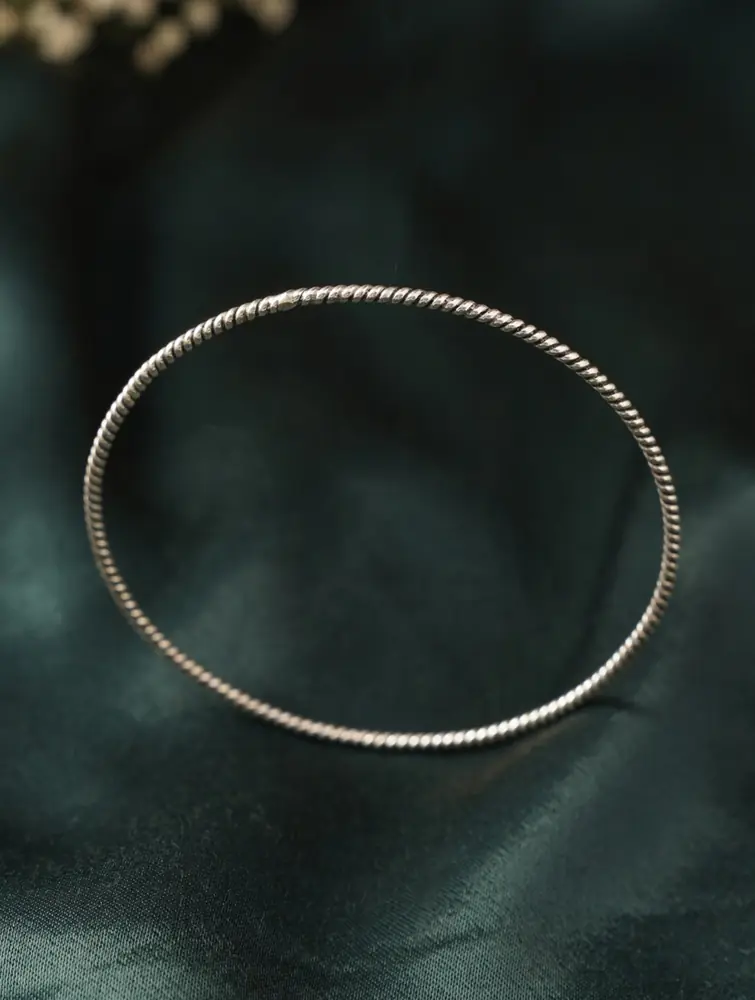Slim textured silver bangle on dark green cloth
