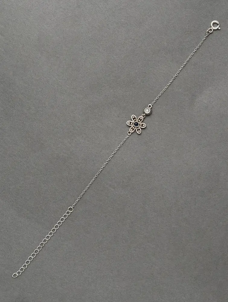 Full length of the silver chain bracelet laid flat on grey